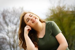 A woman sitting outside and smiling with her eyes closed.